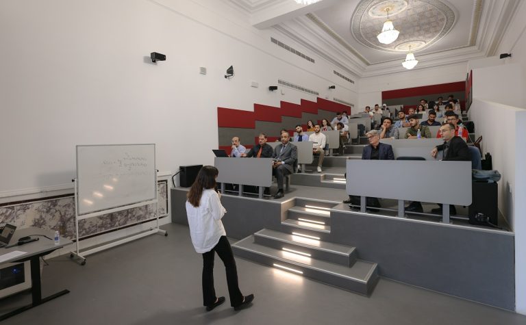 Lecture hall filled with students listening to a faculty member.